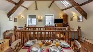 A dining area with a high ceiling, wooden beams, a TV, and a bookshelf. - 2 Bed in Bideford (oc-77915) (Appledore)