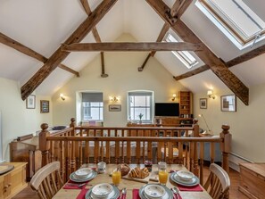 A dining area with a high ceiling, wooden beams, a TV, and a bookshelf. - 2 Bed in Bideford (oc-77915) (Appledore)