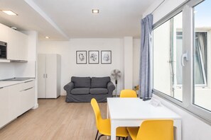 En moderne stue med et køkken, spiseplads og en sofa.