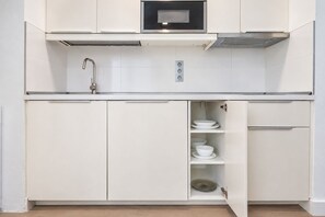 Et moderne køkken med hvide skabe, en indbygget ovn og et opvaskstativ.