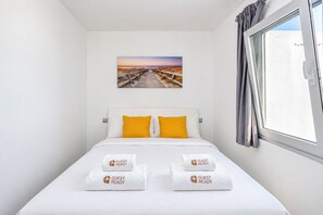 Ein Hotelzimmer mit einem Bett, zwei Kissen, einem Fenster mit Vorhängen und einem Bild an der Wand.