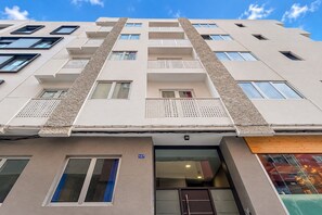 En bygning med flere etager, en flad facade, flere altaner og en indgang i stueplan.