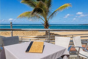 Ein Tisch mit Speisekarte, Stühlen und Blick auf Strand und Meer.