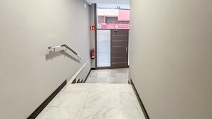 A hallway with a handrail, a fire extinguisher, and a door with a sign. - GuestReady - Artiles Near Canteras Beach (Las Palmas de Gran Canaria)