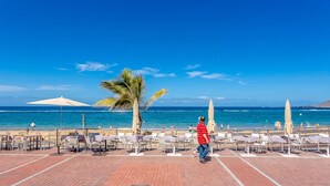 A beachside patio with outdoor seating and umbrellas, overlooking the ocean. - GuestReady - Artiles Near Canteras Beach (Las Palmas de Gran Canaria)
