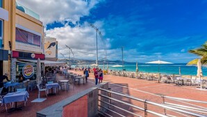 A beachfront area with outdoor seating, a Burger King, and a view of the ocean. - GuestReady - Artiles Near Canteras Beach (Las Palmas de Gran Canaria)