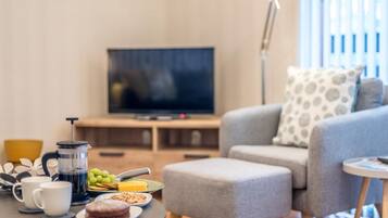 A living room with a sofa, coffee table, and a television.