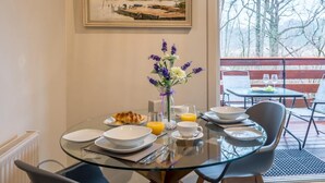 Ein Esstisch mit Tellern, einer Blumenvase und einem Glas Orangensaft.
