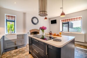 A modern kitchen with a central island, built-in appliances, and a fireplace.