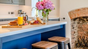 A modern kitchen with a breakfast setup including bread, fruit, and a glass of orange juice. - 5 Bed in Wellington (oc-77900) (Ashbrittle)