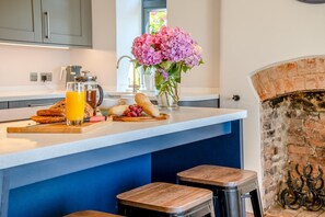 A modern kitchen with a breakfast setup including bread, fruit, and a glass of orange juice.