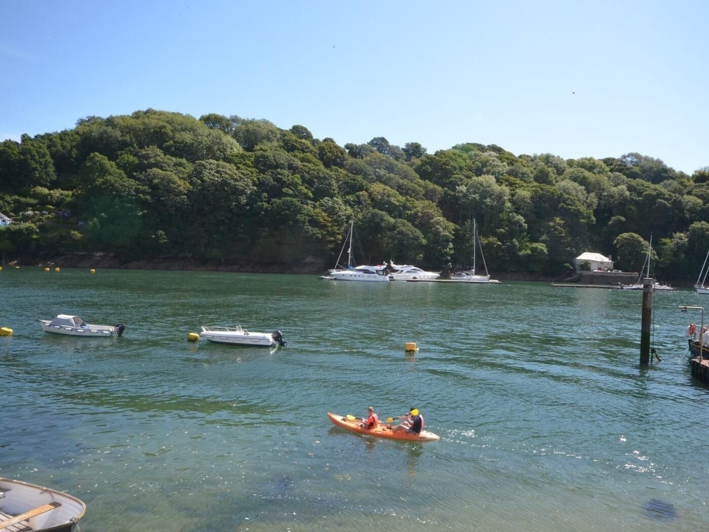 A calm lake with boats, a forested shore, and a clear sky.