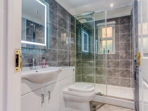 Ein modernes Badezimmer mit einer Duschkabine, einem weißen Waschbecken und einer Toilette.