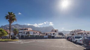 A parking lot with cars, a stop sign, and buildings with red-tiled roofs.