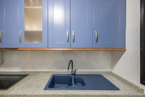 A kitchen with blue cabinets, a double sink, and a wooden countertop.