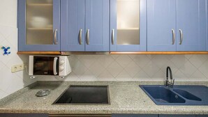 A kitchen with blue cabinets, a microwave, a sink, and a stove.