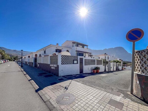 A residential building with a white facade, a gated entrance, and a no parking sign.
