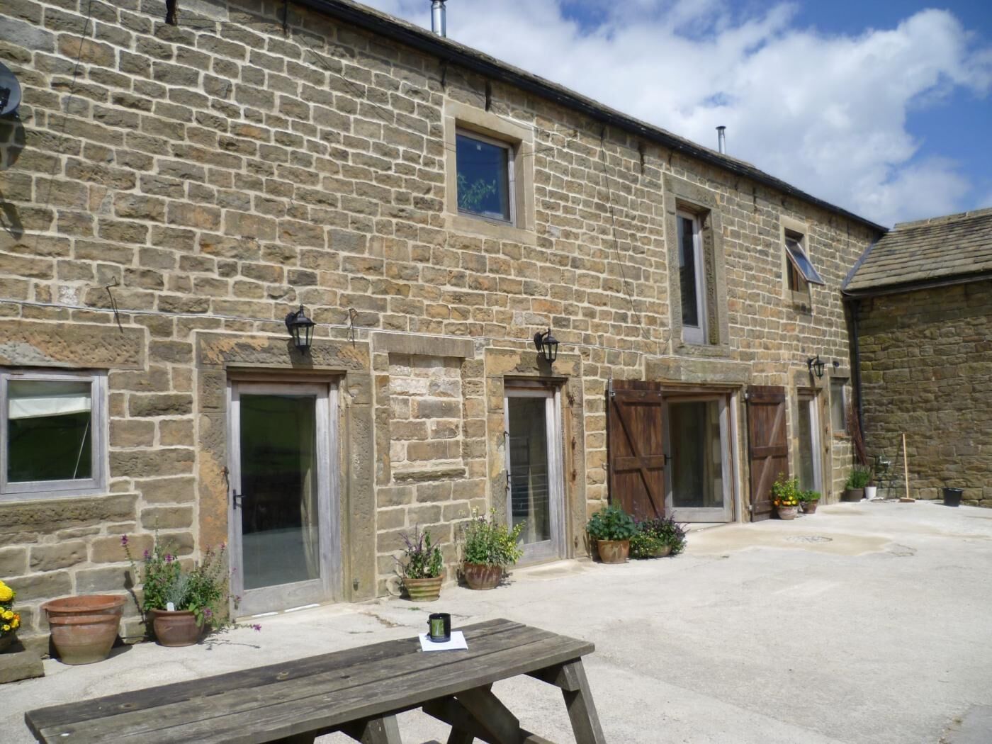 A stone building with multiple doors and windows, a wooden bench, and potted plants.