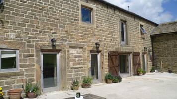 A stone building with multiple doors and windows, a wooden bench, and potted plants.