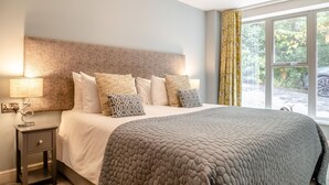 A bedroom with a bed, bedside table, lamp, and a window with curtains. - 1 Bed in Matlock (oc-78225) (Paddocks)