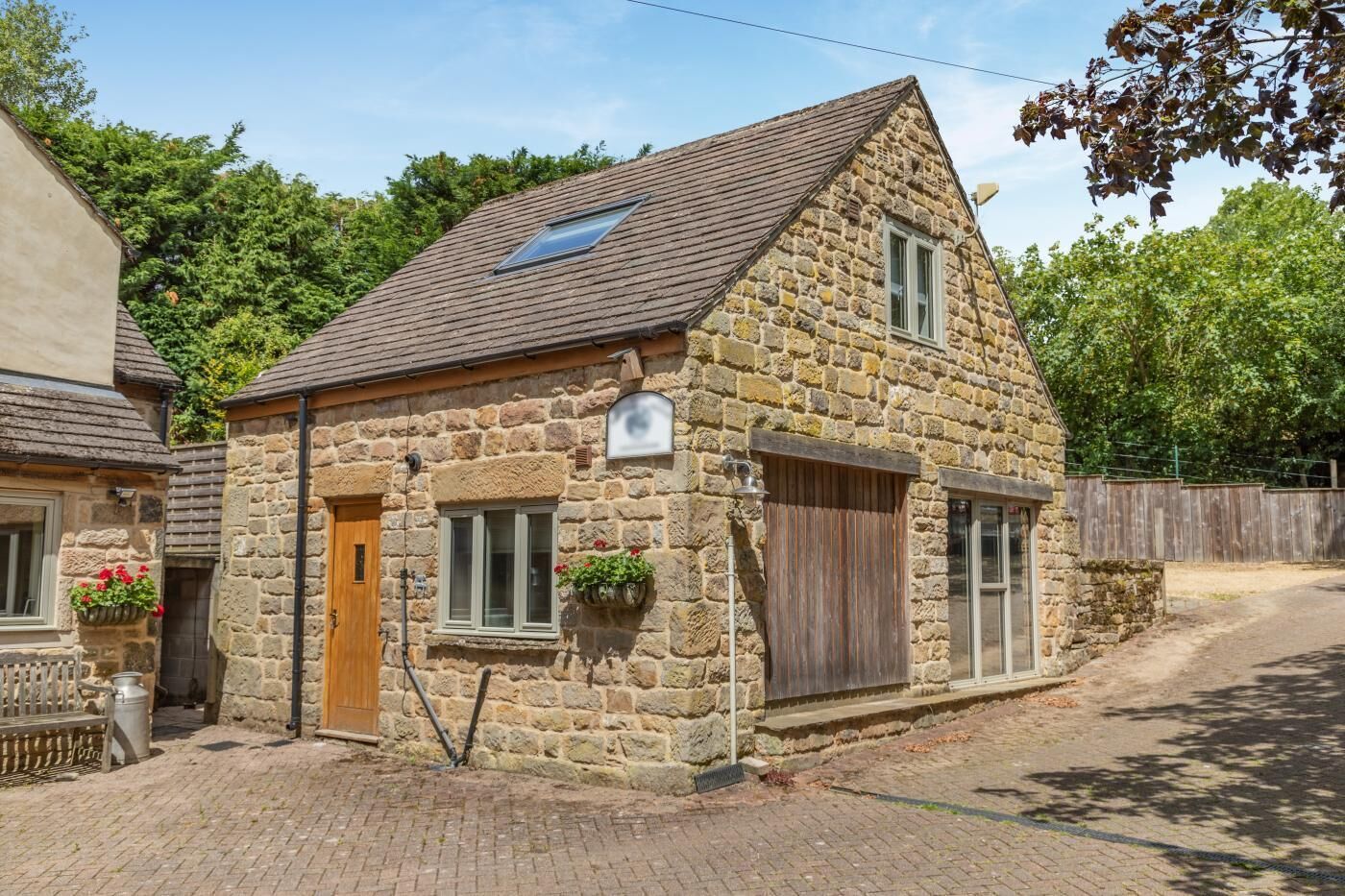 Une maison en pierre avec un toit à deux versants, une petite fenêtre agrémentée d’une jardinière et une porte en bois.