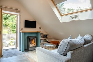 Una sala de estar acogedora con chimenea, un sofá, una estantería y un televisor.