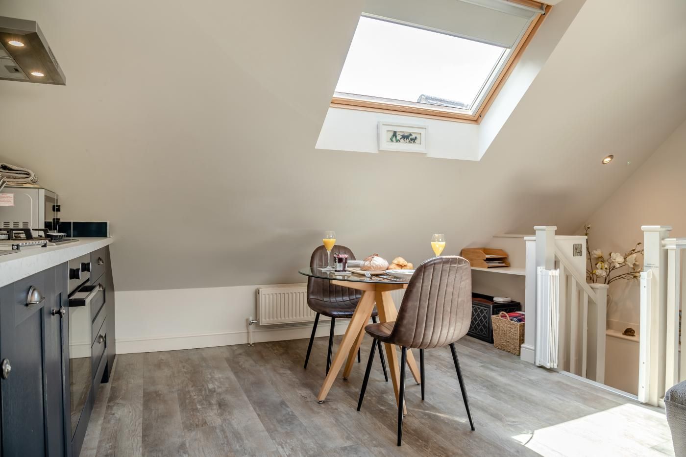 A dining area with a table, chairs, and a view of the sky through a skylight.