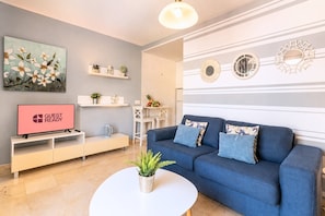 Ein modernes Wohnzimmer mit einem blauen Sofa, einem Flachbildfernseher, einem Couchtisch und Wanddekoration.