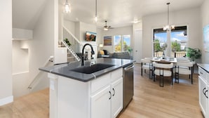 Una cocina moderna con una isla central, armarios blancos y un comedor con una mesa redonda y sillas.