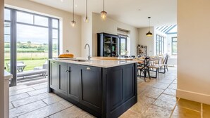 A kitchen with a large island, dark cabinetry, and pendant lighting. - 5 Bed in Llanymynech (oc-80686) (Llanymynech)