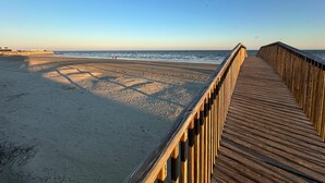 A wooden boardwalk leading to a sandy beach with the ocean in the background. - True Beachfront Condo - Steps to Sand! No Seawall Crossing. 7.7 miles from Port. (Galveston)