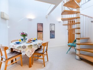 A dining area with a round table, chairs, and a spiral staircase. - 1 Bed in Tenby (oc-fb057) (Tenby)