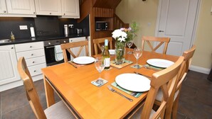 Comedor con mesa de madera dispuesta para cuatro personas, rodeada de sillas de madera.
