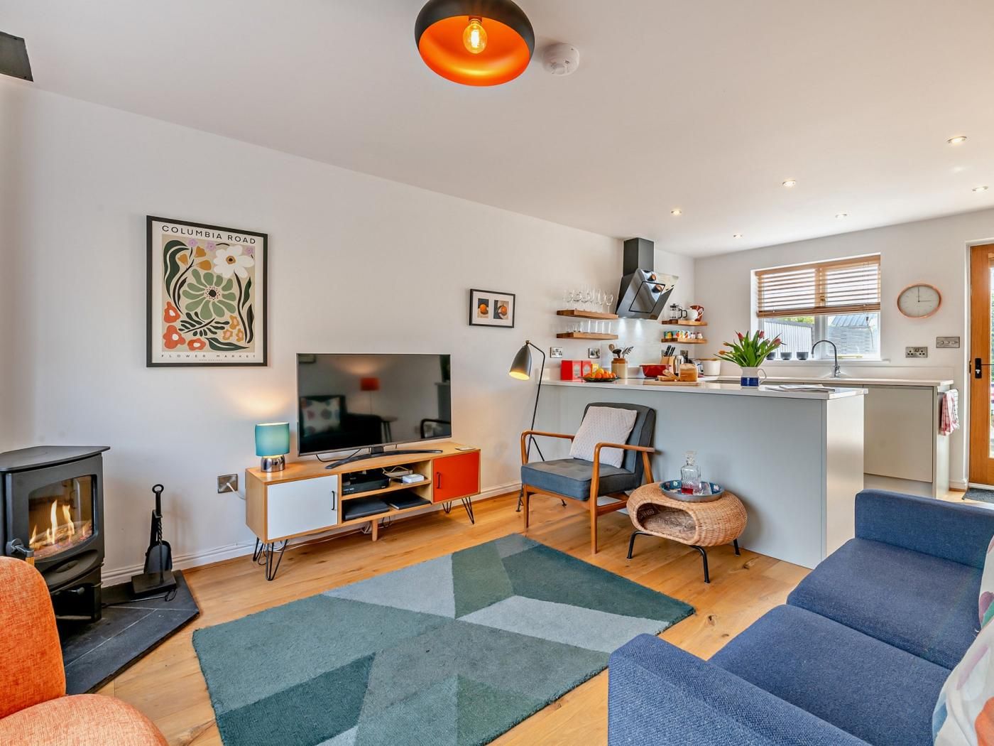Ein modernes Wohnzimmer mit Kamin, Fernseher und Sofa.