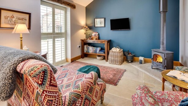 Un salon chaleureux avec un plafond haut, une cheminée, un téléviseur et un coin salon confortable.