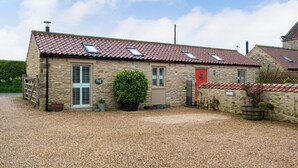 Un bâtiment en pierre avec un toit recouvert de tuiles rouges, une enseigne indiquant qu’il s’agit d’un chalet, et une allée gravillonnée.