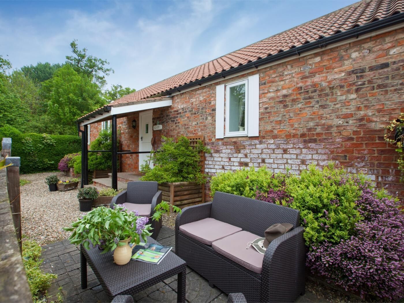 A brick house with a patio, outdoor seating, and potted plants.
