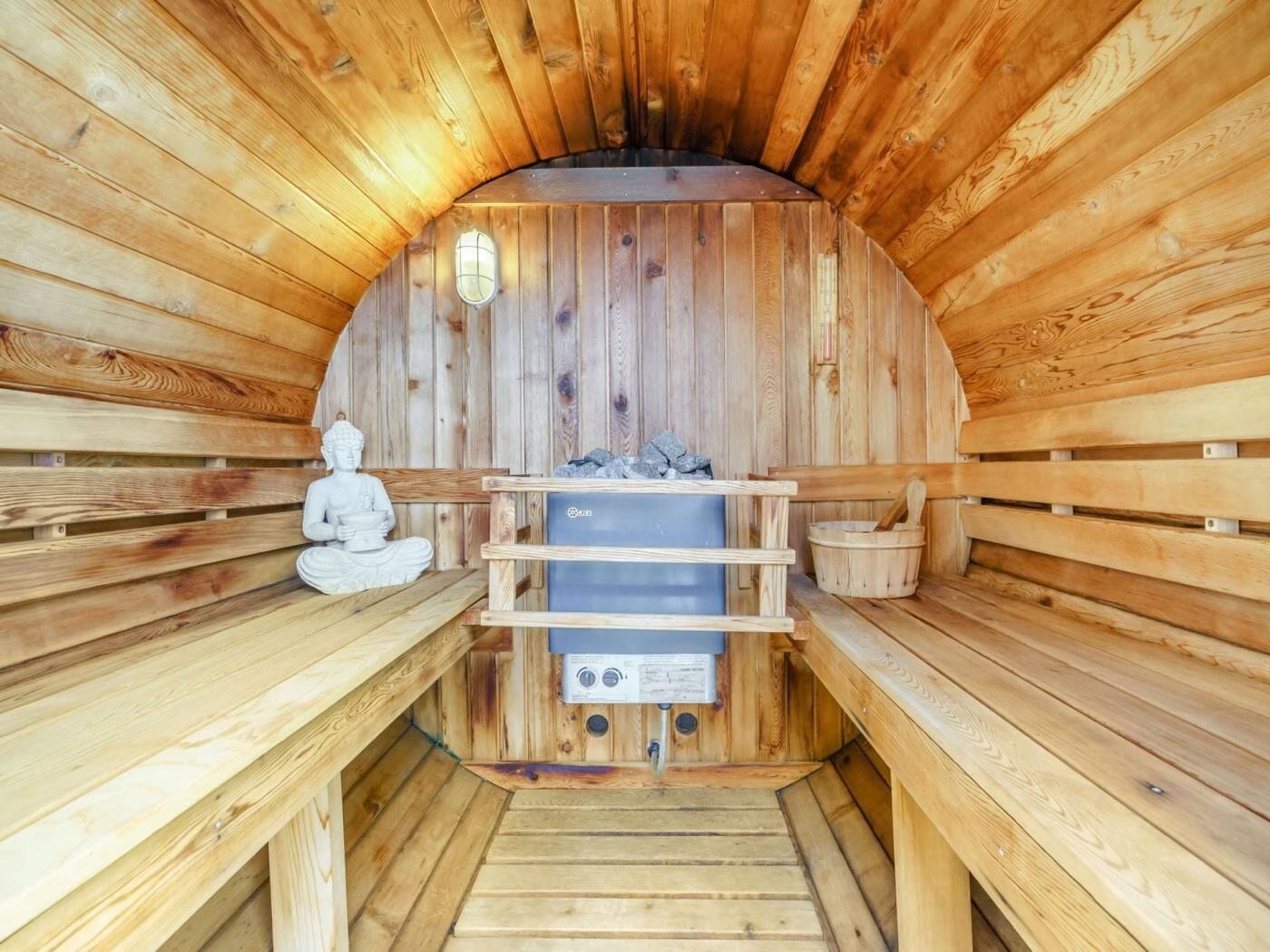 A sauna with wooden benches, a statue, and a sauna heater.