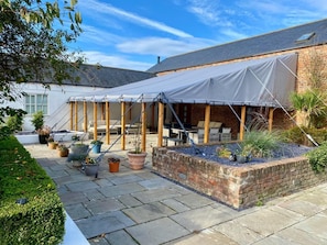 Eine überdachte Terrasse mit Gartenmöbeln und Topfpflanzen.