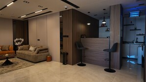 A modern living area with a sofa, coffee table, and a small kitchen area with a bar stool. - Sahat Al Khaleej Serviced Apartments (Riyadh)