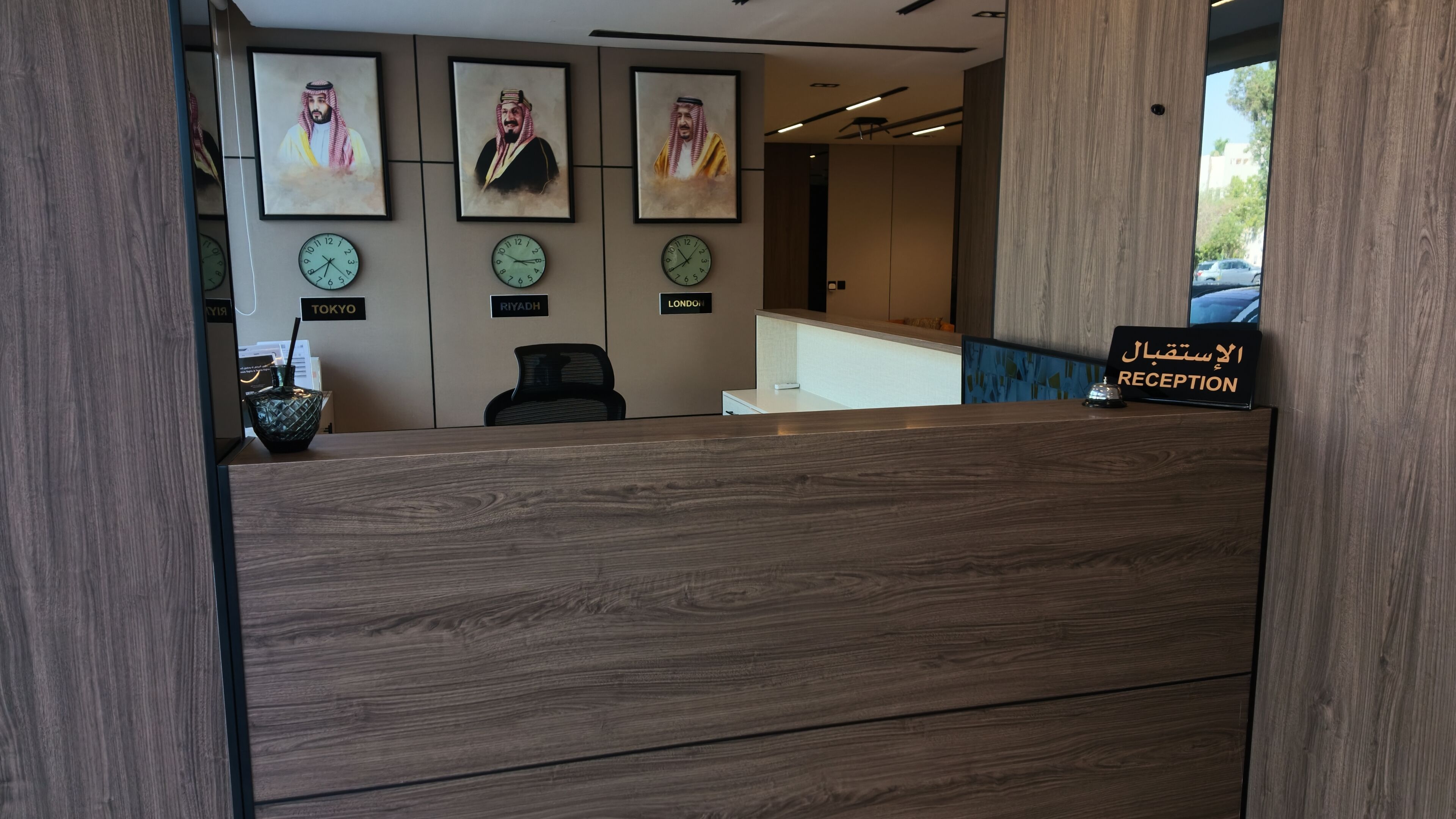 A reception desk with clocks labeled 'TOKYO,' 'RIYADH,' and 'LONDON,' and a sign in Arabic reading 'RECEPTION.'