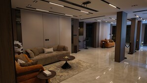 A modern living room with a sofa, armchair, coffee table, and a decorative vase. - Sahat Al Khaleej Serviced Apartments (Riyadh)