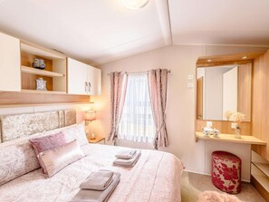 Ein Hotelzimmer mit einem Bett, einem Nachttisch, einer Lampe und einem Spiegel.