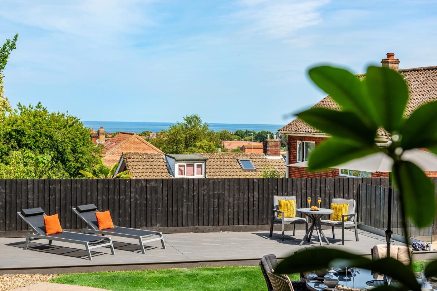 Un patio con mobili da esterno, vista mare e recinzione in legno.