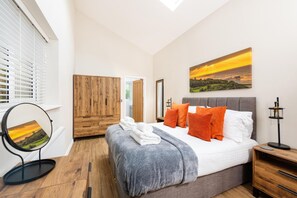 A bedroom with a bed, a wooden wardrobe, a painting, and a mirror. - 4 Bed in Cromer (oc-82588) (Cromer)