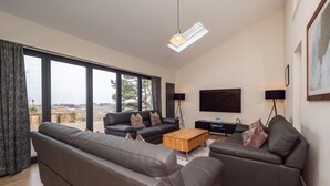 A modern living room with a large sofa, a smaller sofa, a coffee table, and a flat-screen TV. - 4 Bed in Cromer (oc-82588) (Cromer)