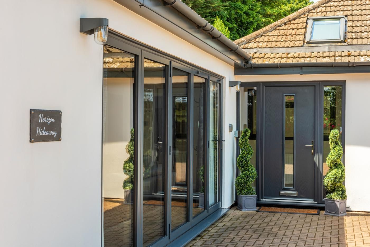 A modern building with a glass door entrance, a sign reading 'Horizon Hideaway,' and a tiled roof.