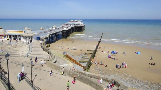 A beach with a pier, a promenade, and a large shipwreck. - 4 Bed in Cromer (oc-82588) (Cromer)