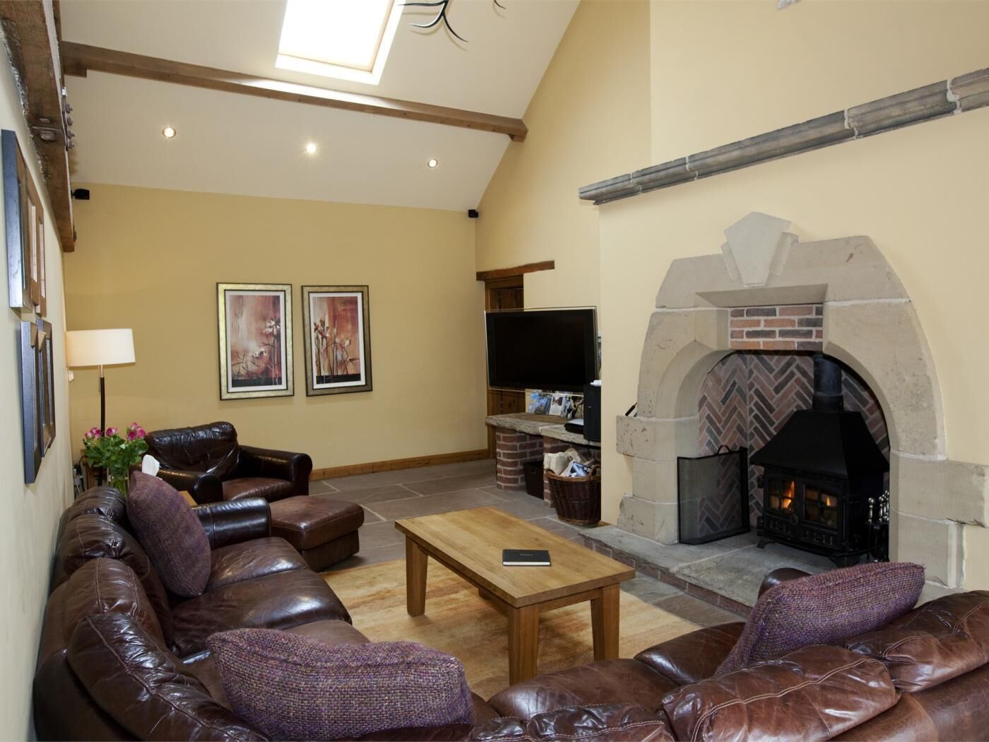 A living room with a leather sofa, a wooden coffee table, a fireplace, and a television.