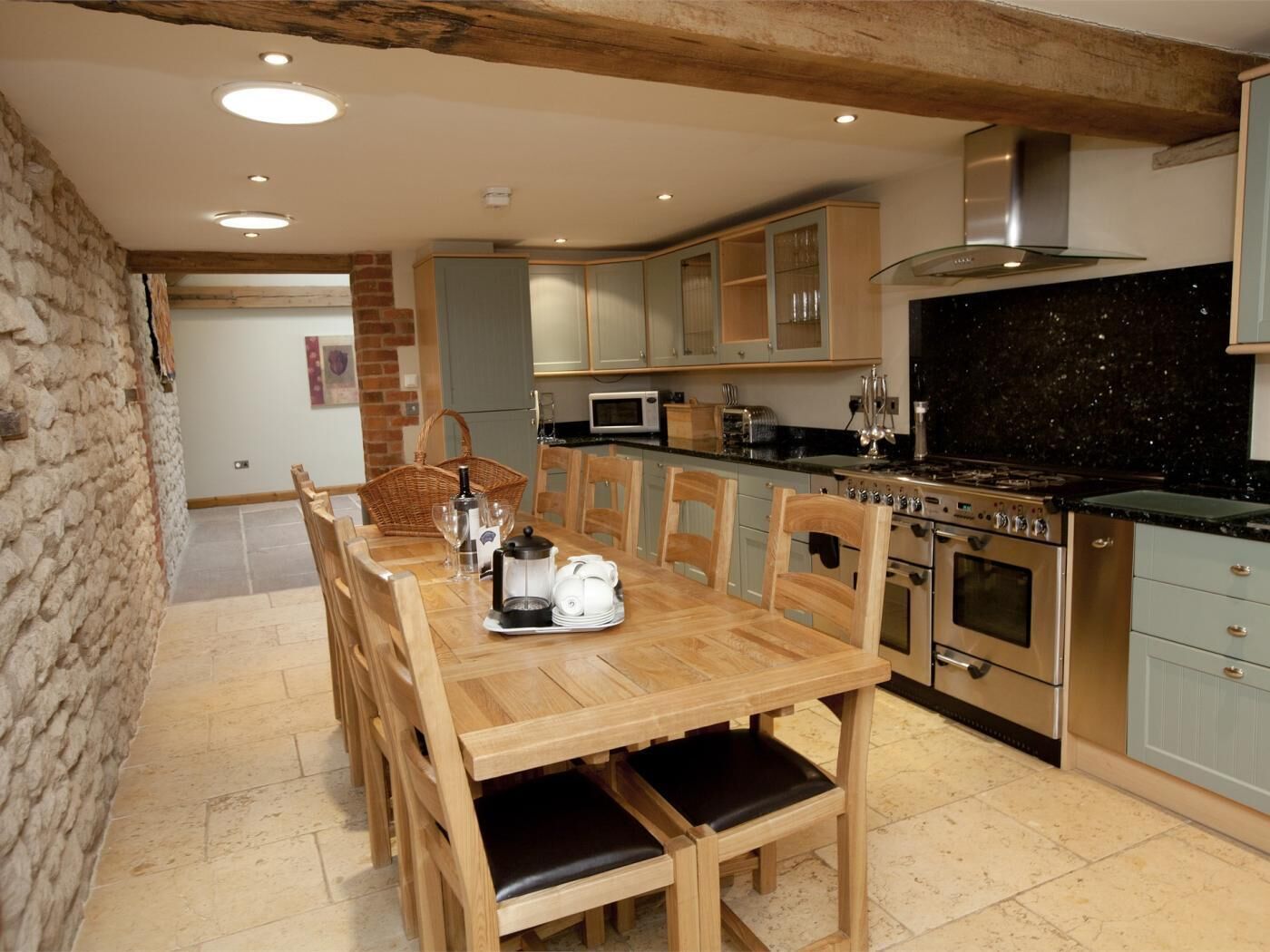 Una cocina con una mesa de madera, sillas, estufa y armarios.